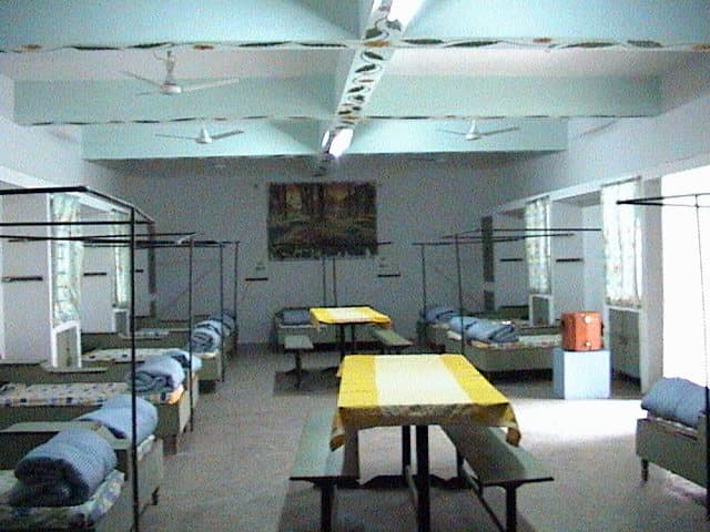 A dormitory at Radiant: beds with rolled bedding, study tables, ceiling fans