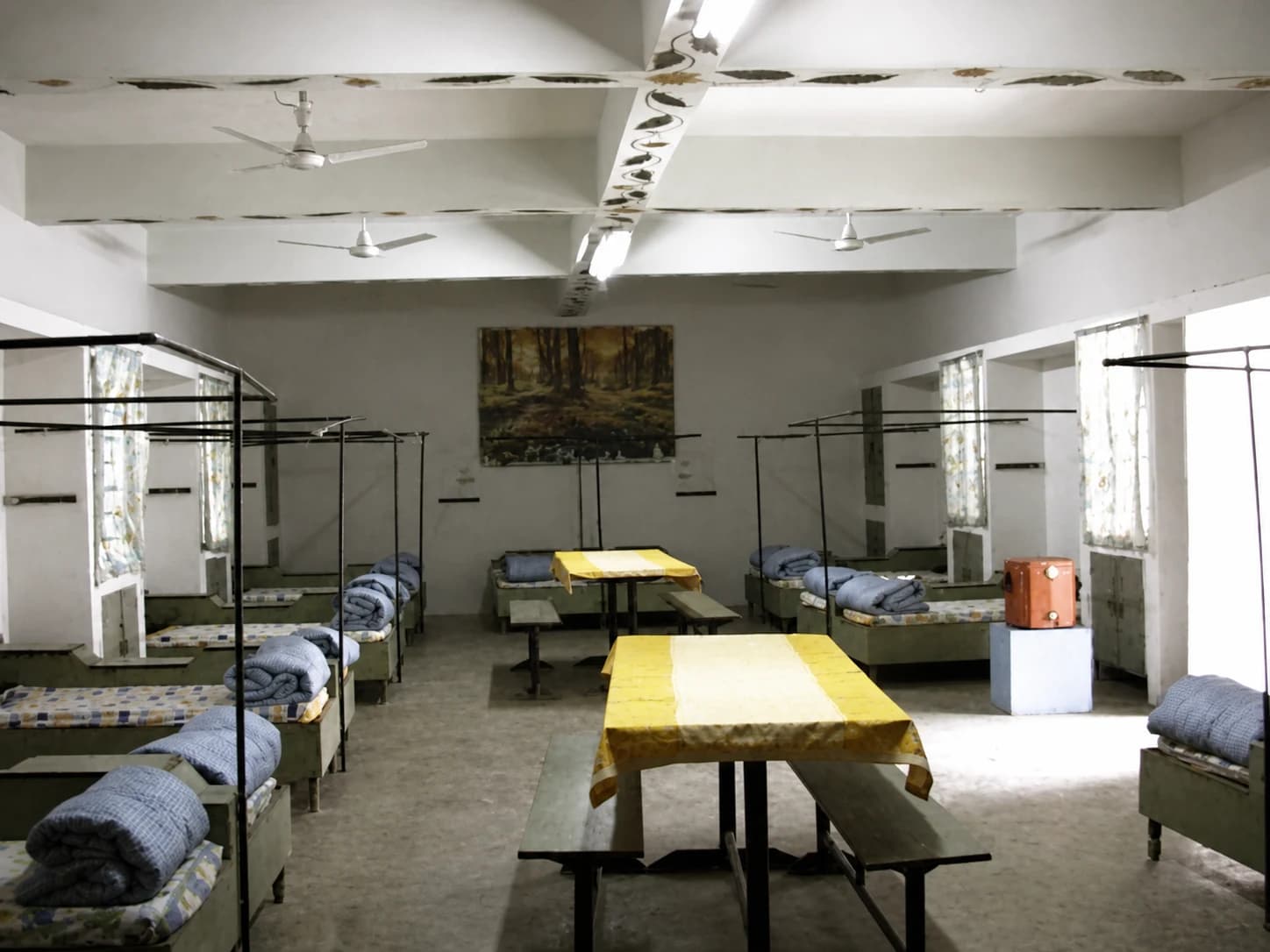 A dormitory at Radiant: beds with rolled bedding, study tables, ceiling fans